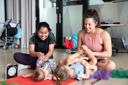 Two women leaning in to play with infants