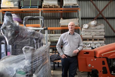 Smiling man in a factory, surrounded by goods