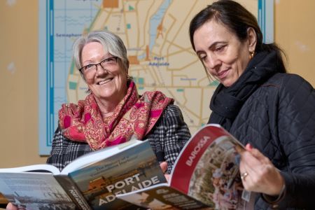 Two women smiling, in front of a large historic map
