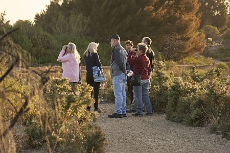 People on a walking tour with binoculars at sunset o