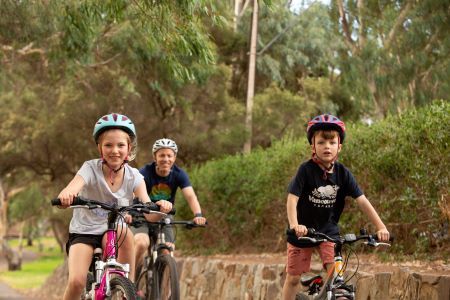 Dad and two kids cycling along path