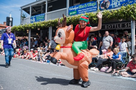 Woman dressed as an elf riding an inflatable reindeer