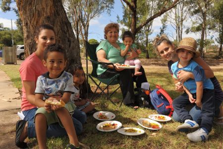 Group of women of varying ages with children on their laps, sitting in a park