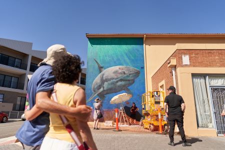 Spectators watching a shark mural being applied